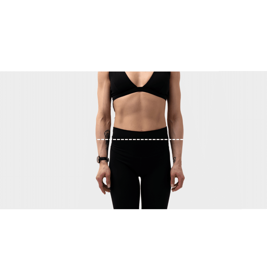 Woman demonstrating proper hip measurement technique with measuring tape around widest part of hips